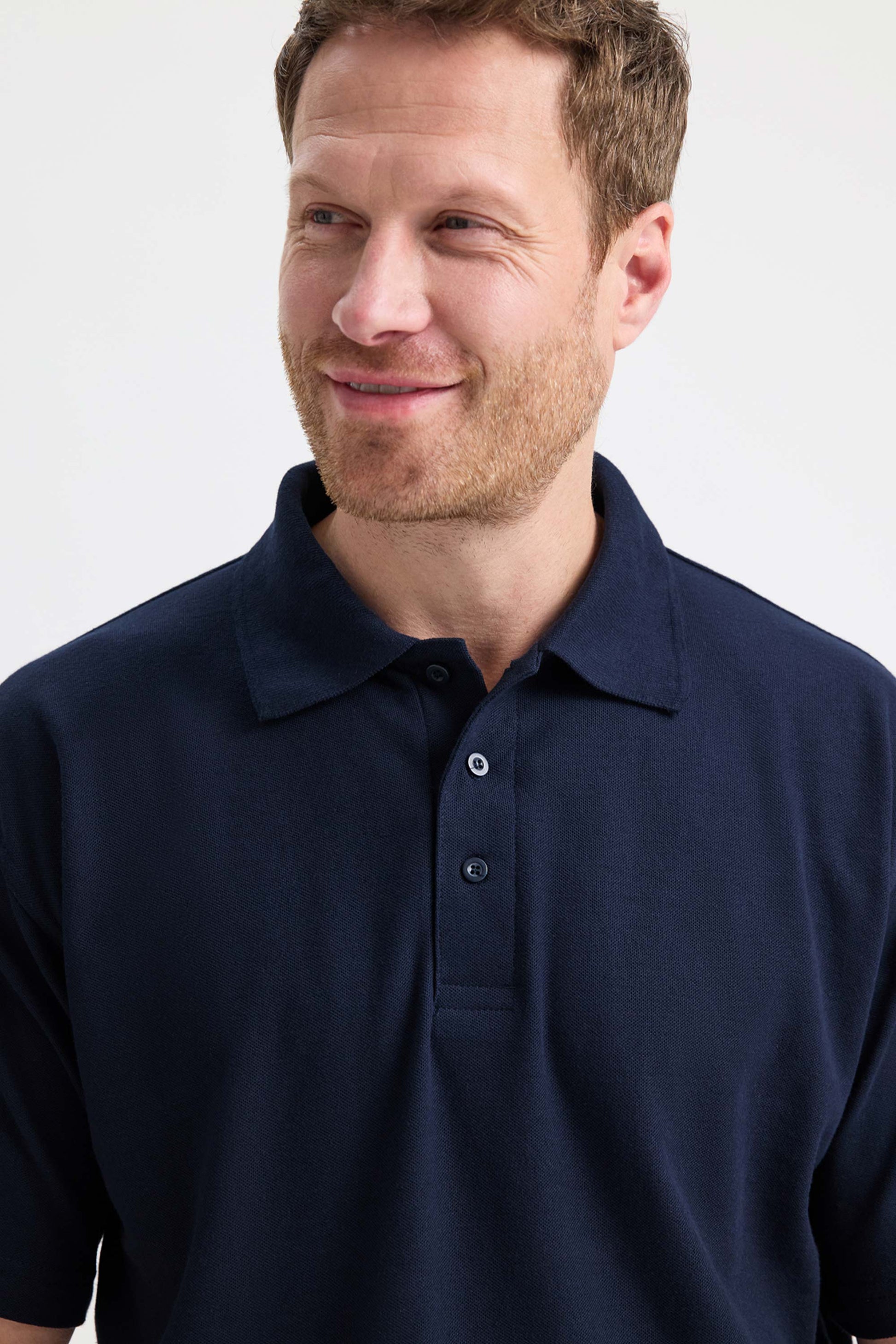 Man wearing a navy blue polo shirt against a white background