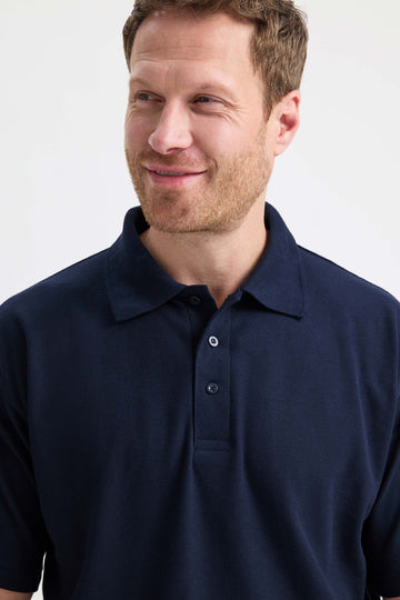 Man wearing a navy blue polo shirt against a white background