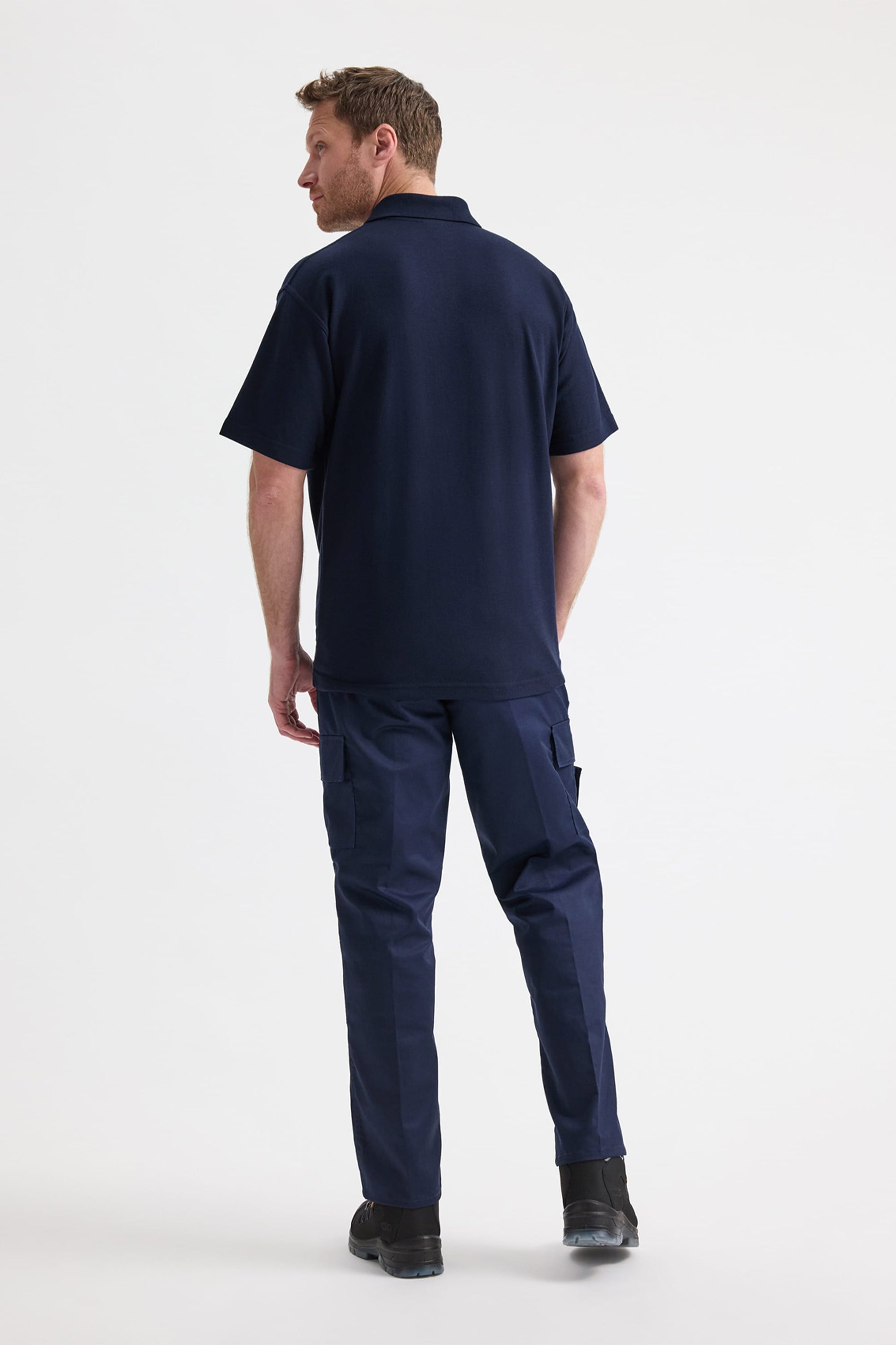 Man wearing a navy blue polo shirt and cargo pants on a white background