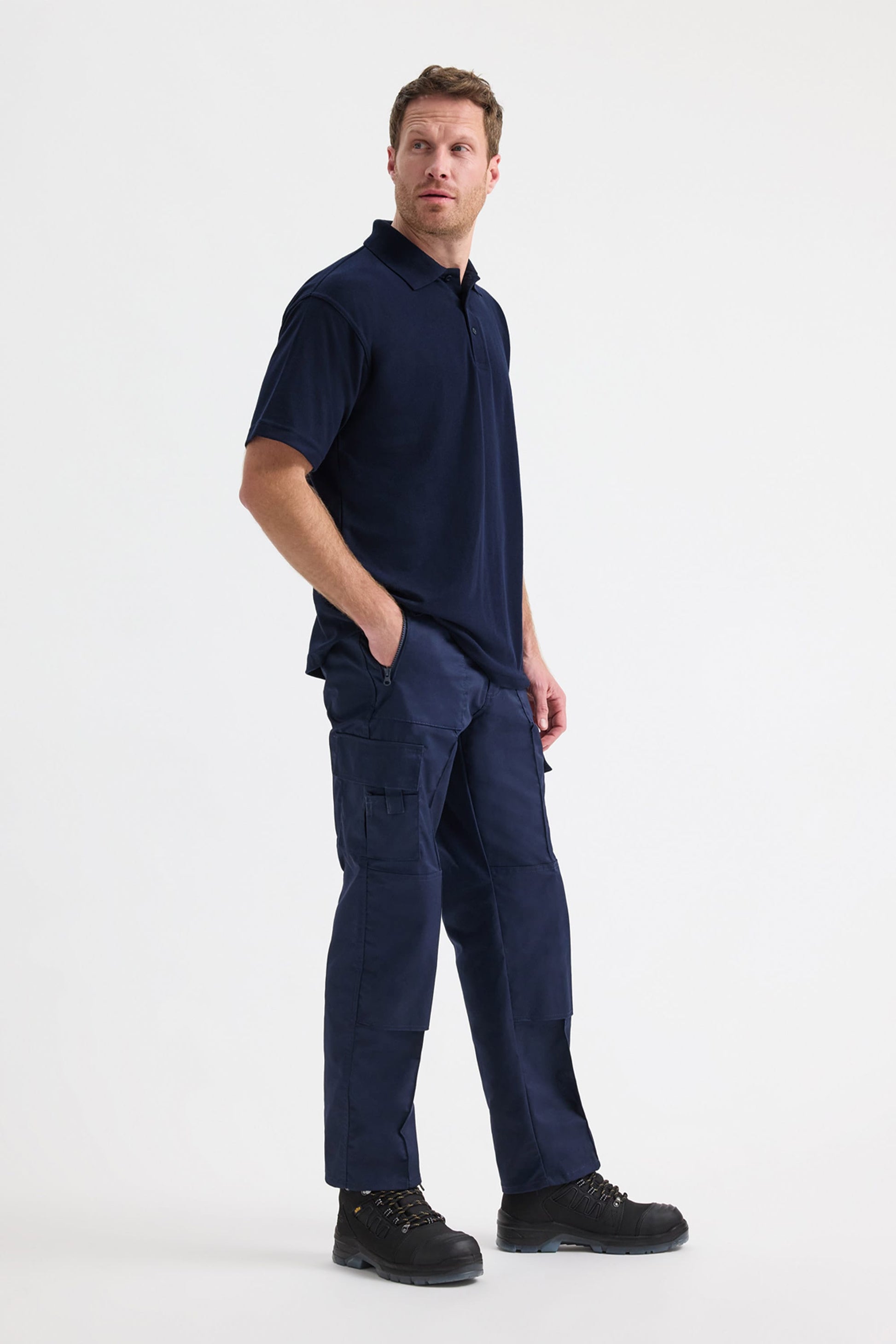 Man wearing a navy blue polo shirt and cargo pants on a white background