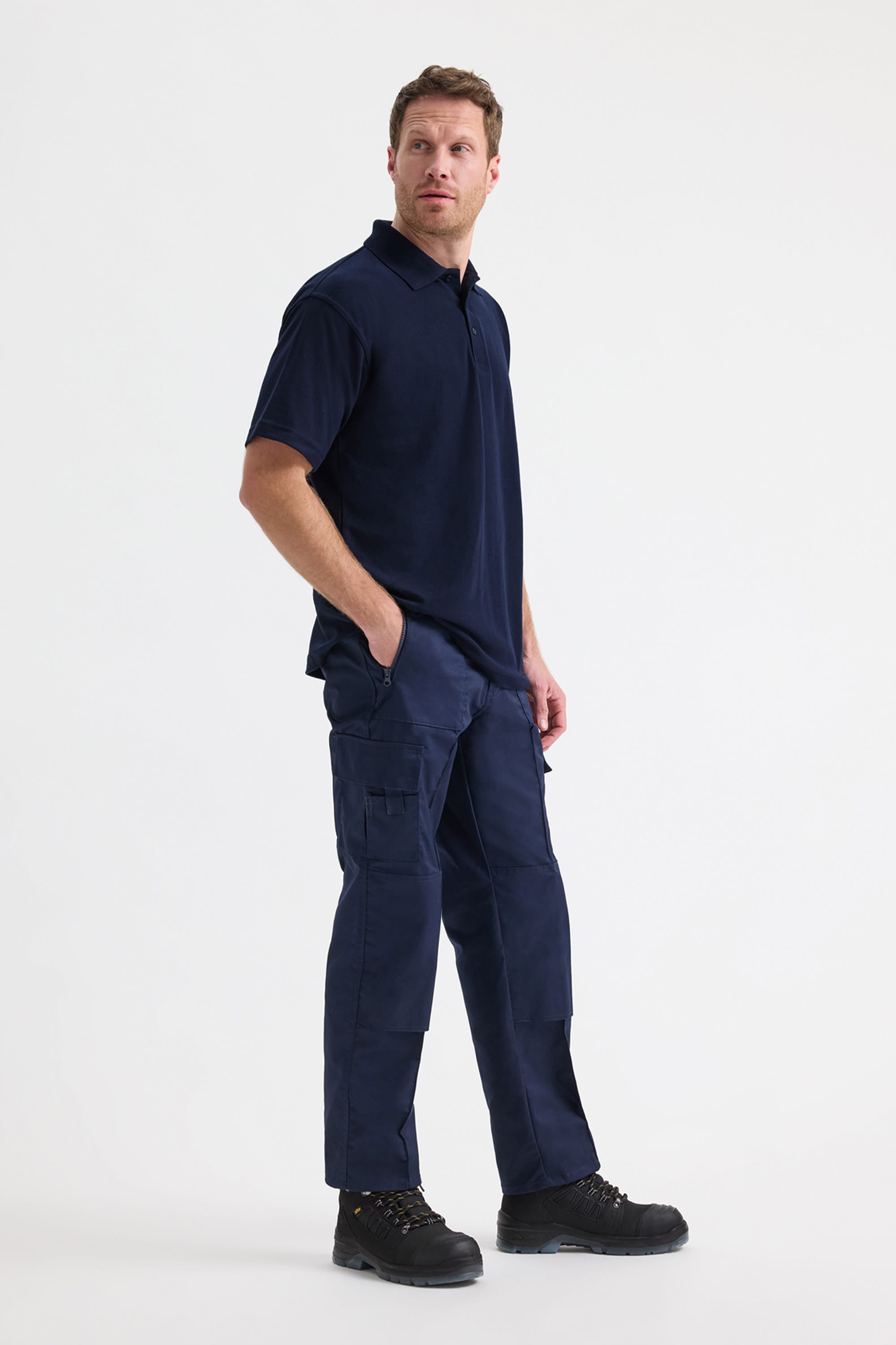 Man wearing a navy blue polo shirt and cargo pants on a white background