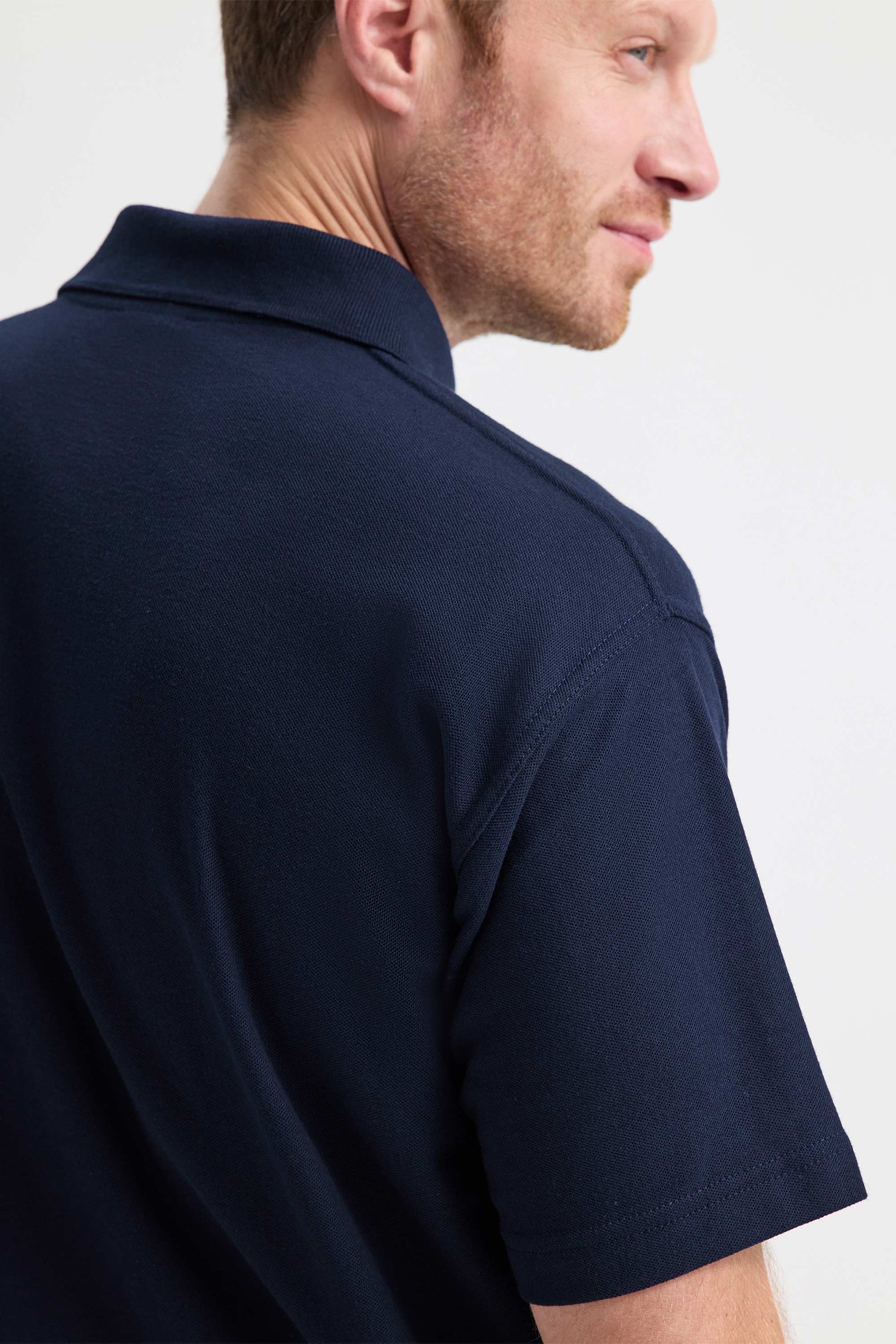 Man wearing a navy blue polo shirt against a white background