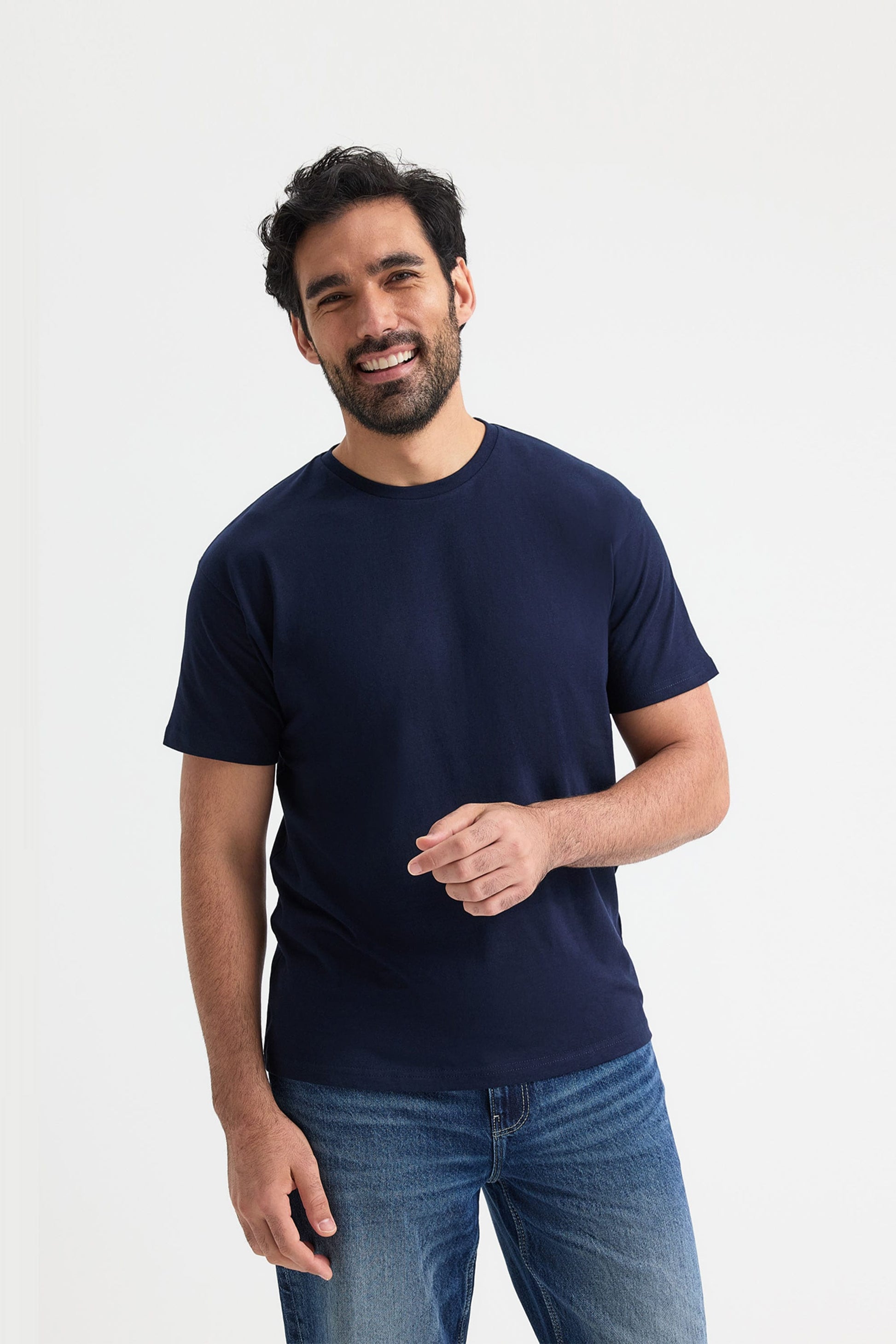 Man wearing a navy blue t-shirt and jeans on a white background