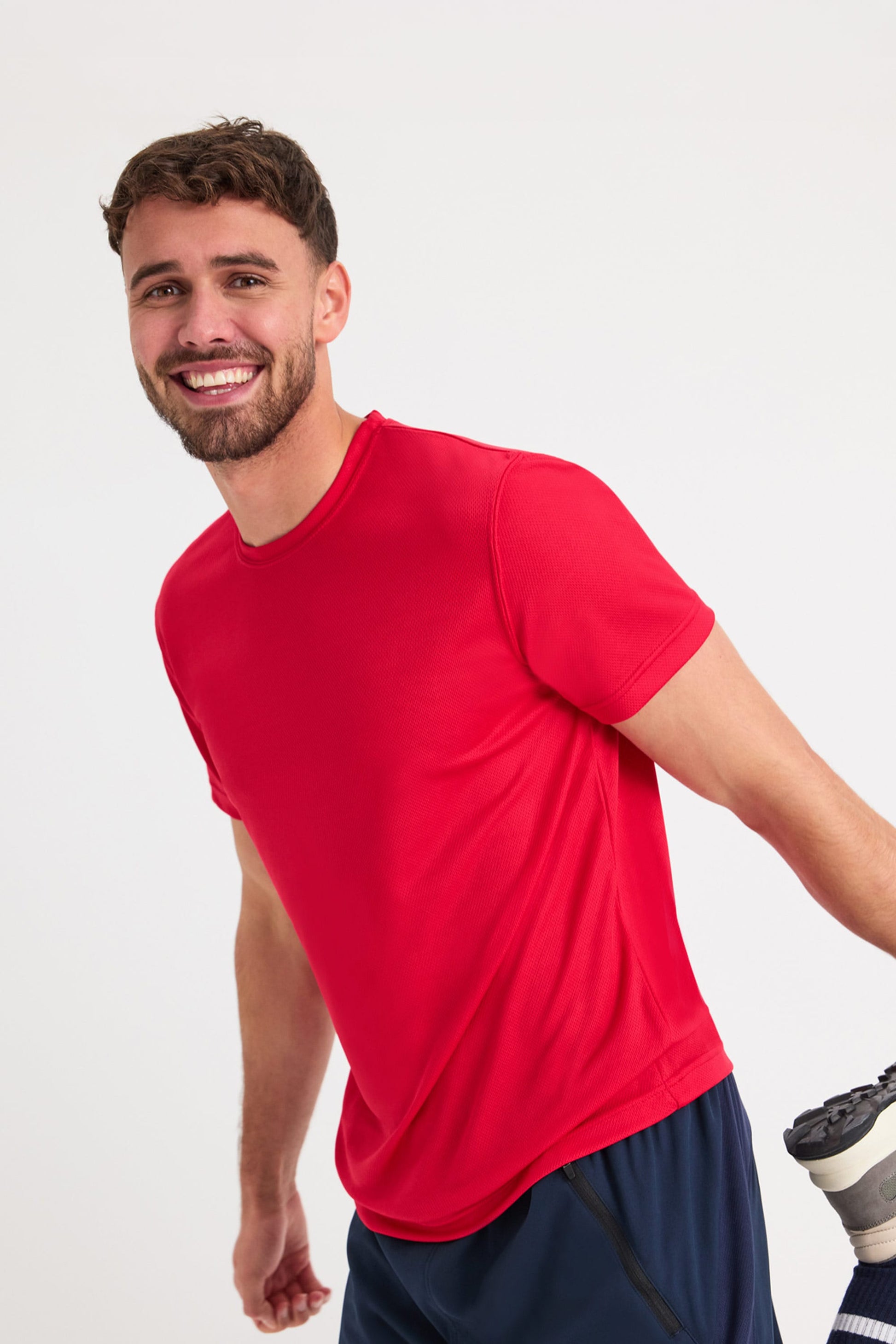 Man wearing a red t-shirt and navy shorts