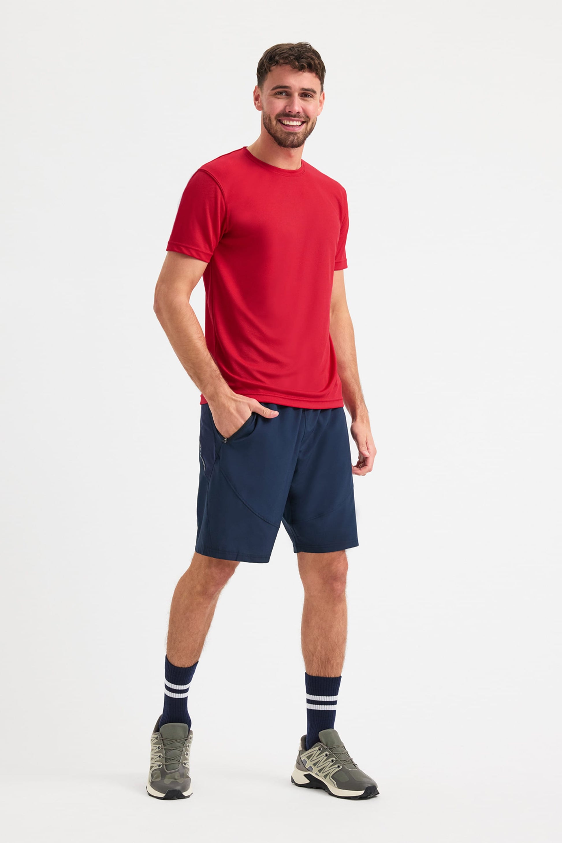 Man wearing a red t-shirt and navy shorts on a white background