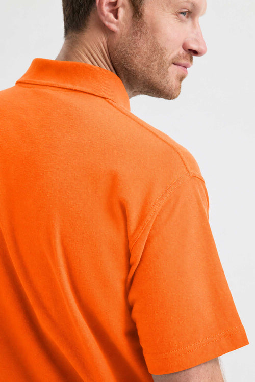 Man wearing an orange polo shirt against a white background