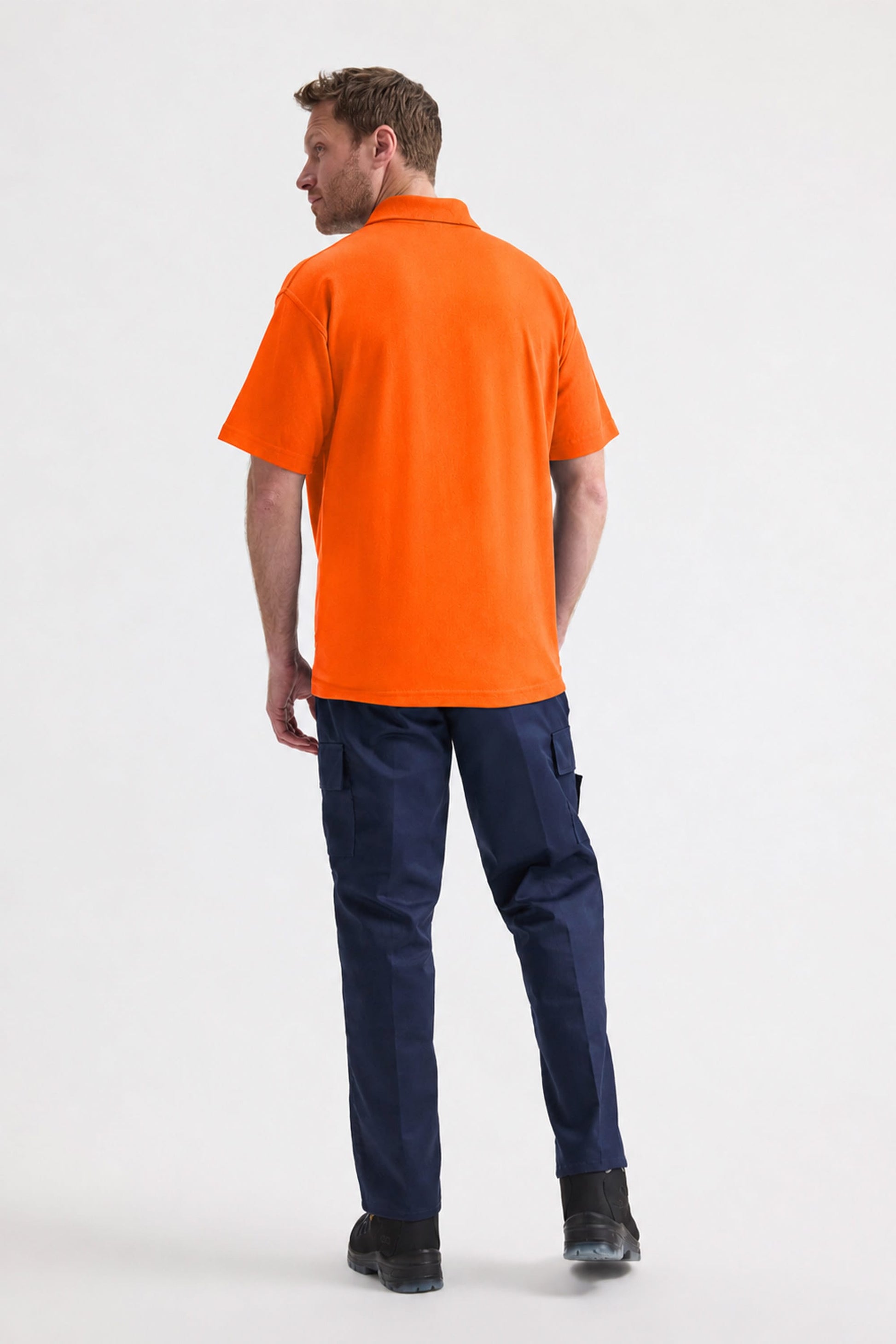 Man wearing an orange polo shirt and navy pants on a white background