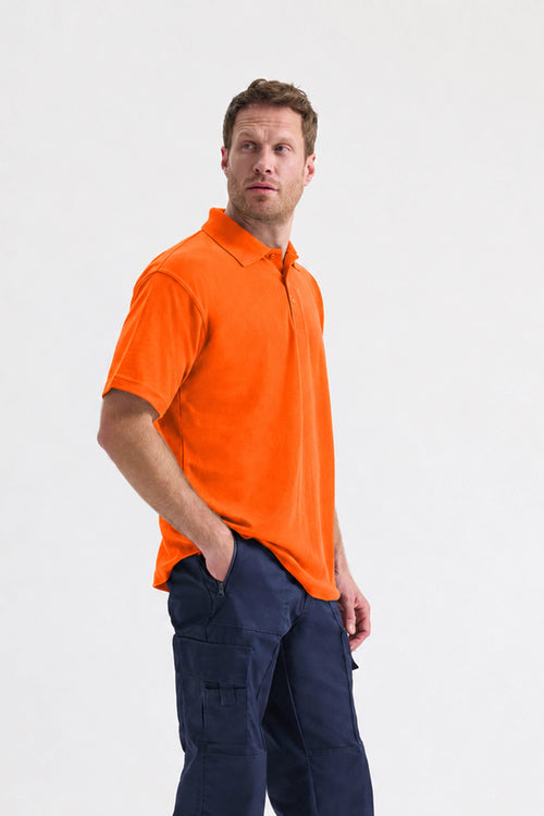 Man wearing an orange polo shirt and navy pants on a white background