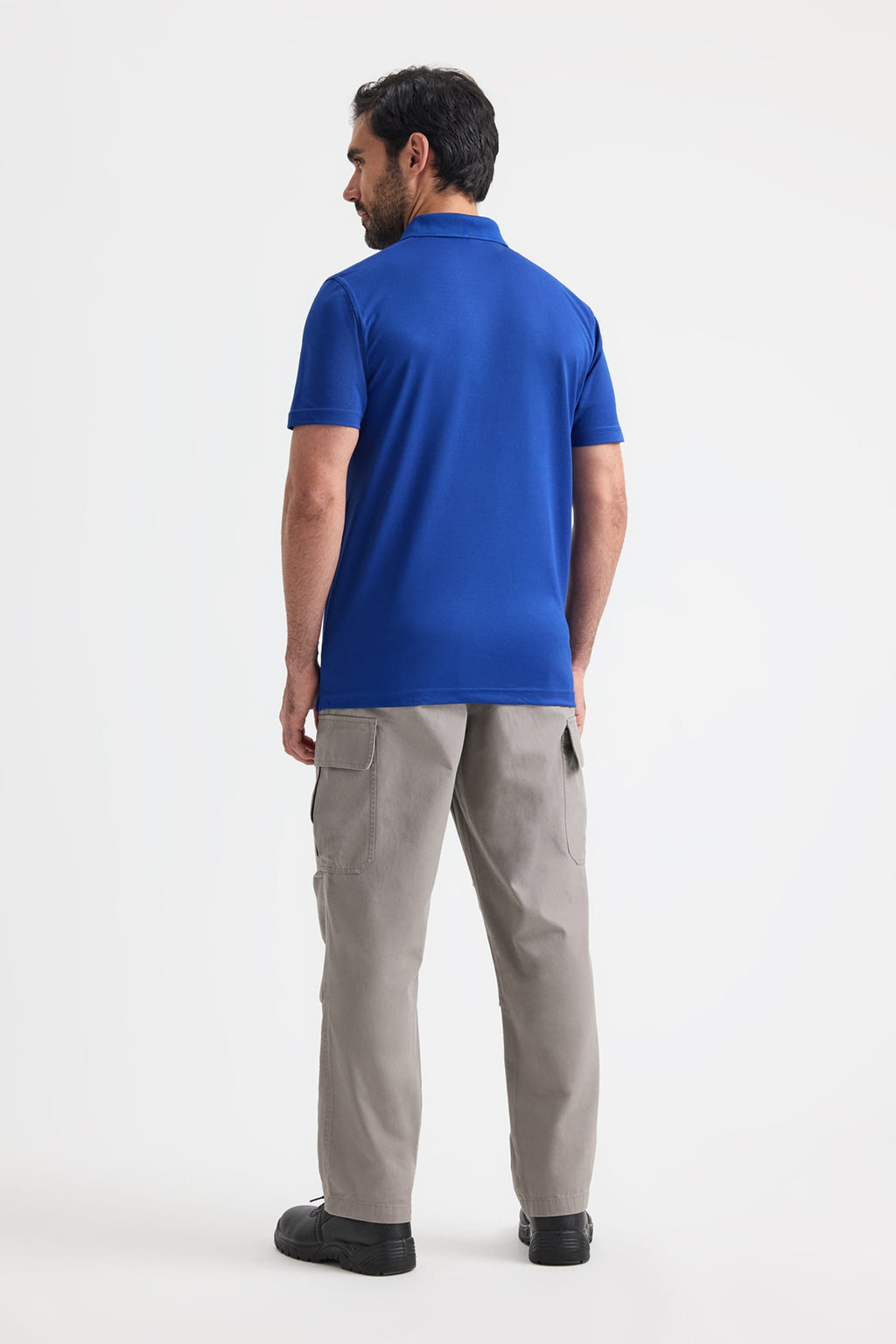 Man wearing a blue polo shirt and grey pants on a white background